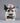 Animated snowman with a small village scene inside, waving and holding a Christmas tree on a black background.