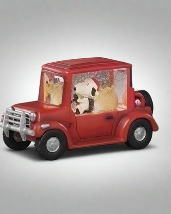 Red toy truck with a snow globe featuring Snoopy and Woodstock on a dark background