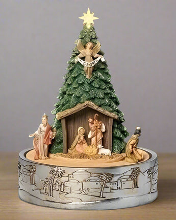Decorative nativity scene with a Christmas tree and star on top, set against a dark background.