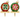 Two decorative Christmas tree ornaments displayed side by side on gold-colored stands against a white background. One ornament is red with green and white starburst detailing, and the other is green with red and pink starburst detailing, both featuring gold caps and loops.