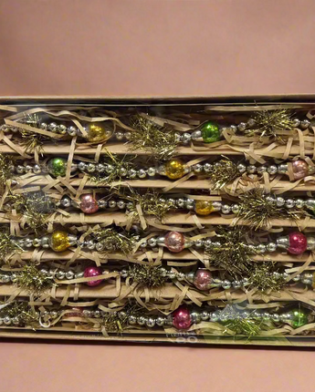 Box of Christmas ornaments with decorative ribbons and beads on a cluttered background